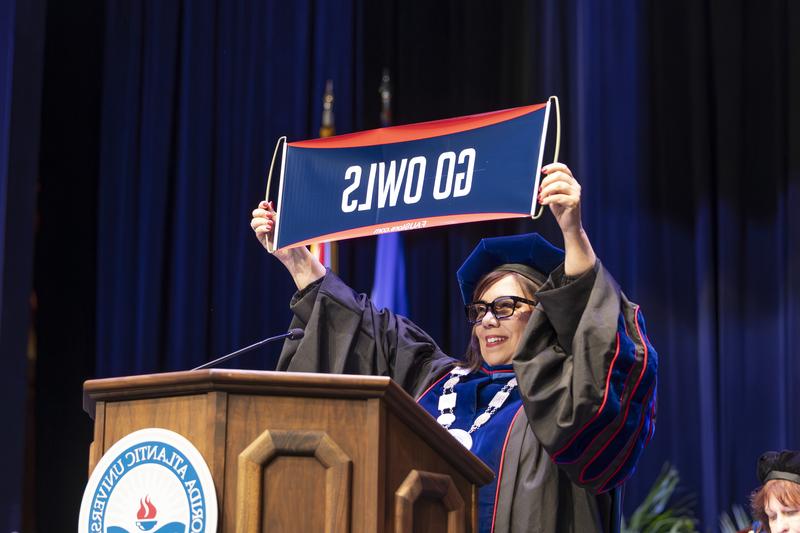 Stacy Volnick holding up "GO OWLS" banner